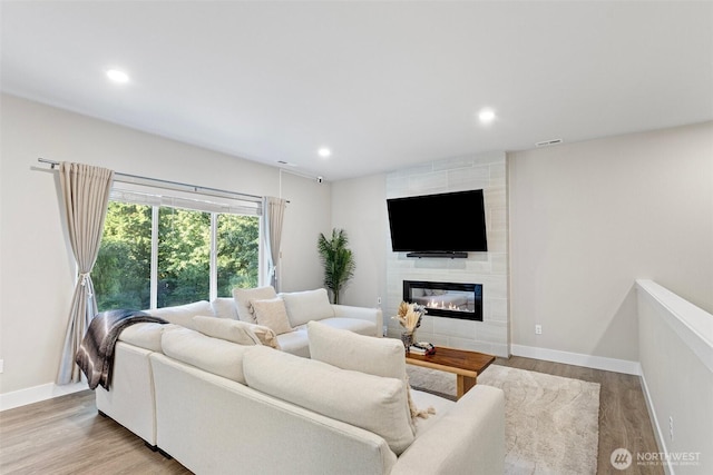 living area featuring wood finished floors, a fireplace, and baseboards