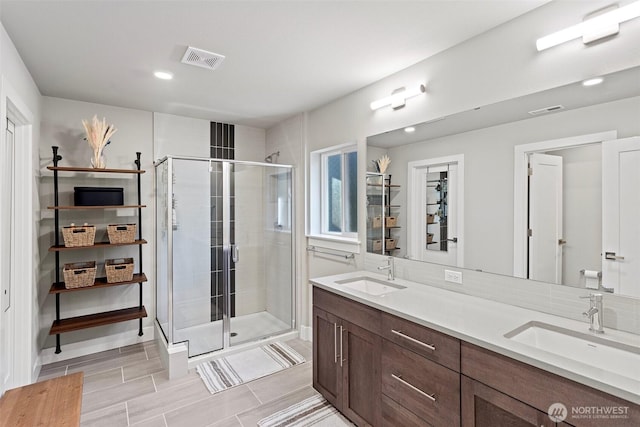 bathroom with a sink, visible vents, and a stall shower