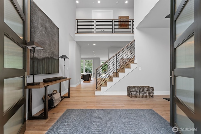 foyer entrance with baseboards, a high ceiling, and wood finished floors