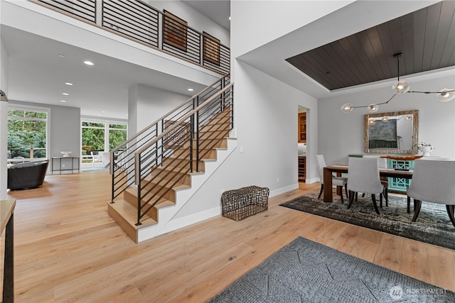 dining room with wood finished floors, baseboards, a tray ceiling, recessed lighting, and stairs