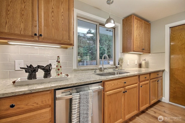 kitchen featuring a sink, decorative light fixtures, light stone counters, and dishwasher