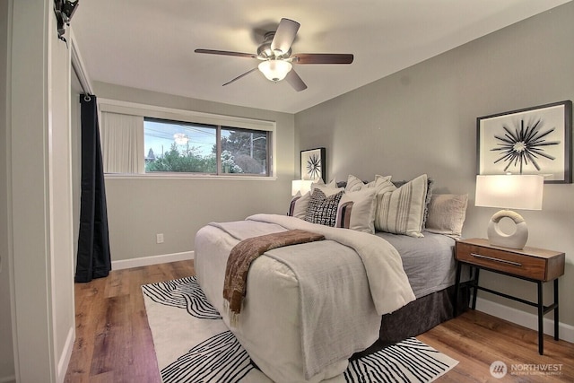 bedroom featuring baseboards, wood finished floors, and a ceiling fan