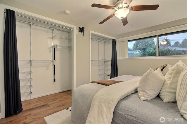 bedroom with baseboards, two closets, wood finished floors, and a ceiling fan