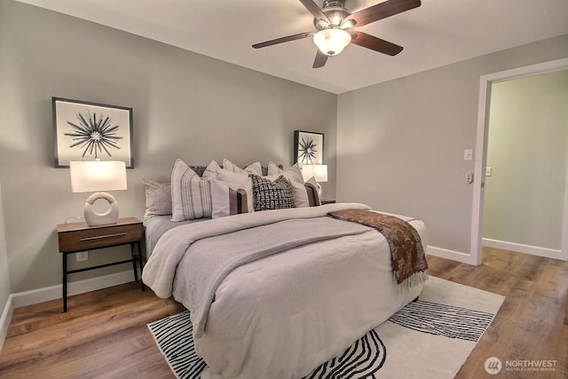 bedroom with a ceiling fan, wood finished floors, and baseboards