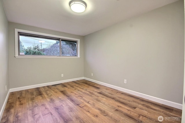 unfurnished room with visible vents, baseboards, and wood finished floors