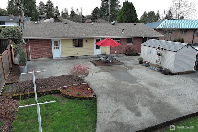 back of property with fence, an outdoor structure, a storage unit, a patio area, and brick siding