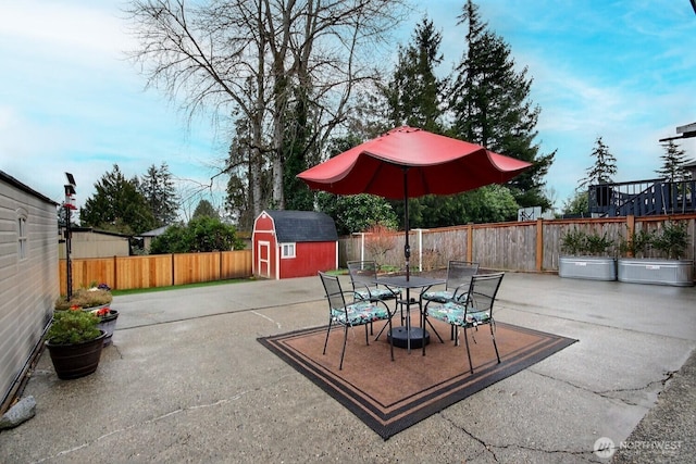 view of patio / terrace featuring outdoor dining space, an outdoor structure, a storage unit, and a fenced backyard