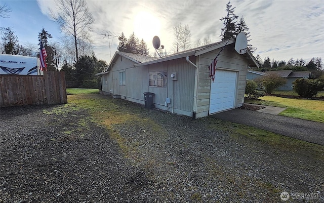 view of home's exterior with aphalt driveway, fence, and a garage