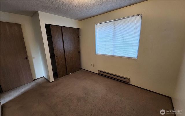 unfurnished bedroom featuring a baseboard radiator, a textured ceiling, a closet, and carpet flooring