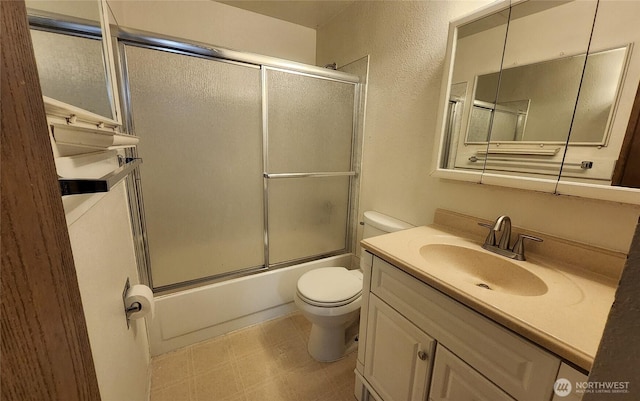 full bath with toilet, a textured wall, tile patterned floors, combined bath / shower with glass door, and vanity