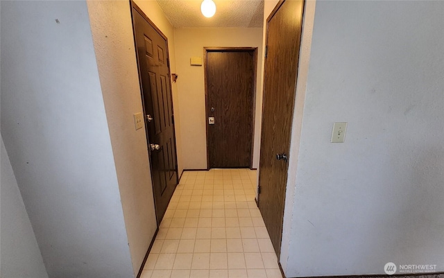 corridor with light tile patterned floors and a textured ceiling