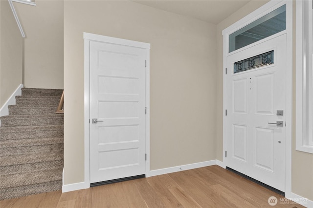 entrance foyer with stairs, baseboards, and wood finished floors