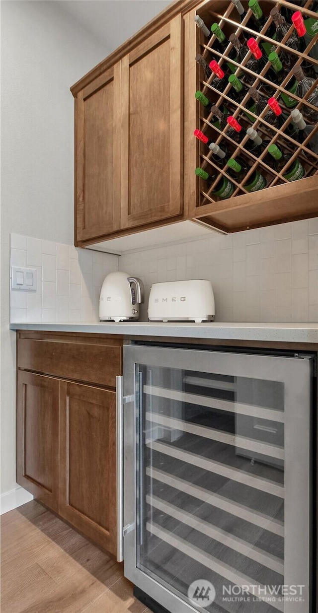 bar featuring beverage cooler, light wood-style flooring, and tasteful backsplash