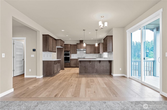 kitchen featuring double oven, dark brown cabinetry, tasteful backsplash, and a sink