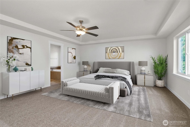 carpeted bedroom featuring a tray ceiling, a ceiling fan, baseboards, and connected bathroom