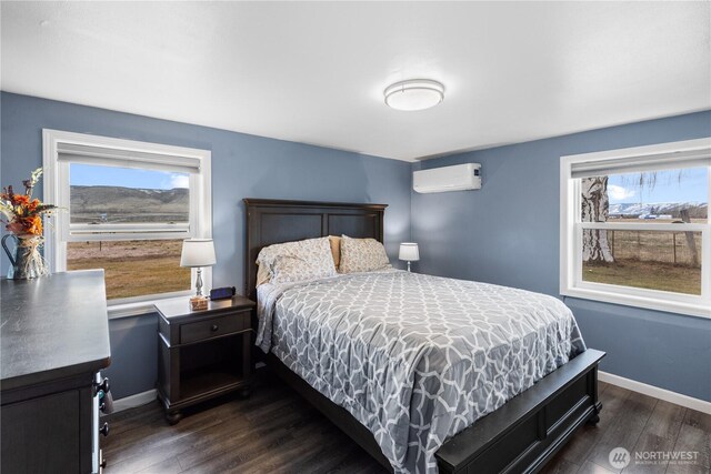 14530 Rutherford Rd, Yakima, WA 98903 - bedroom featuring dark wood-style floors, an AC wall unit, multiple windows, and baseboards