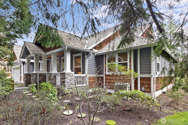 view of front of property with a garage, stone siding, and covered porch