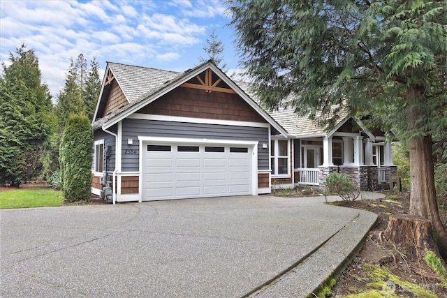 craftsman-style home with a garage, stone siding, covered porch, and concrete driveway