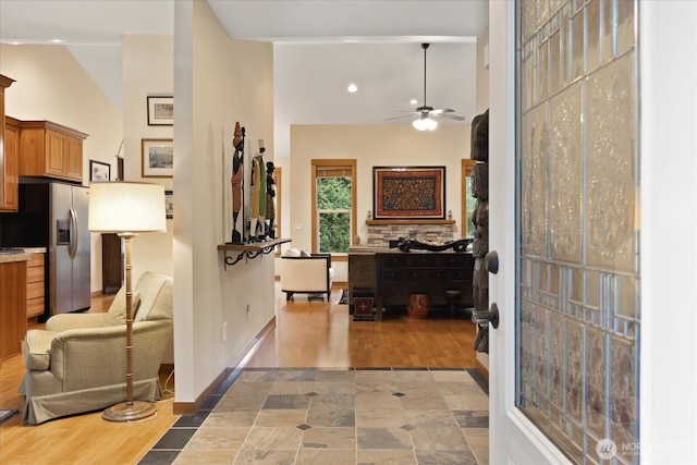 hallway featuring baseboards, high vaulted ceiling, and wood finished floors