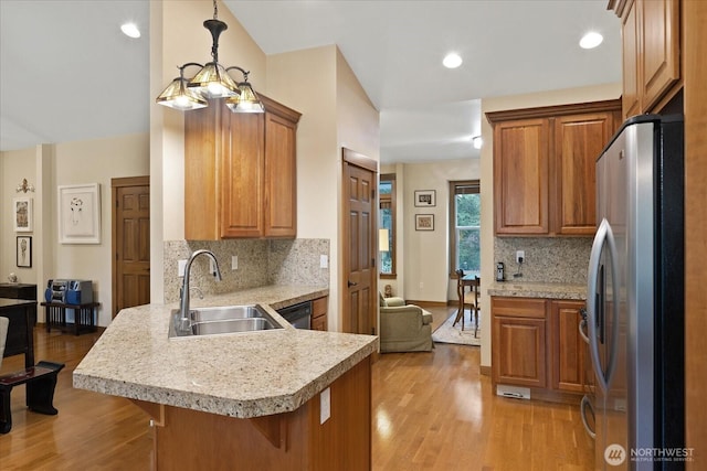 kitchen featuring light wood-type flooring, light countertops, a peninsula, stainless steel appliances, and a sink