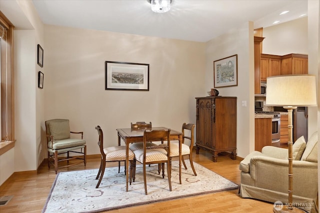 dining space featuring visible vents, baseboards, and light wood finished floors