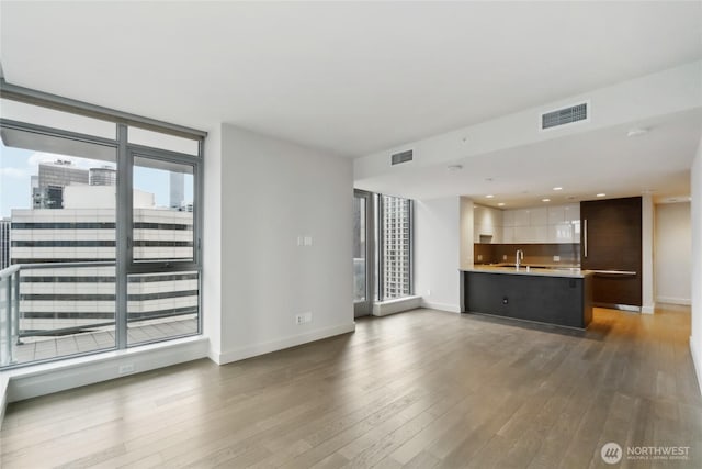 588 Bell St Unit 1603S, Seattle, WA 98121 - unfurnished living room with wood finished floors, baseboards, a sink, and recessed lighting