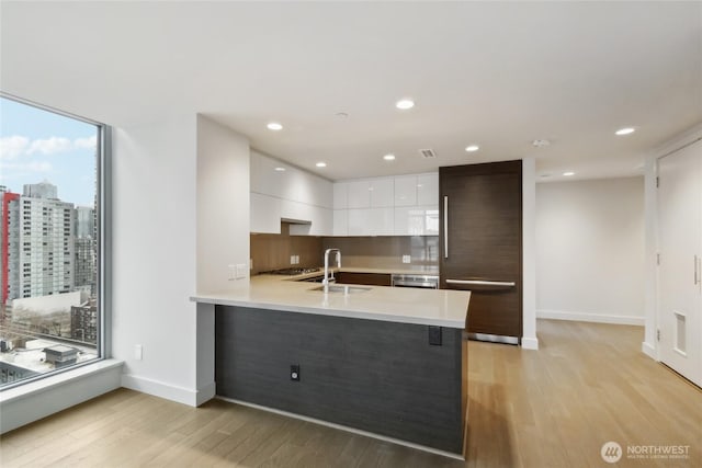 588 Bell St Unit 1603S, Seattle, WA 98121 - kitchen with modern cabinets, light countertops, white cabinetry, light wood finished floors, and built in refrigerator