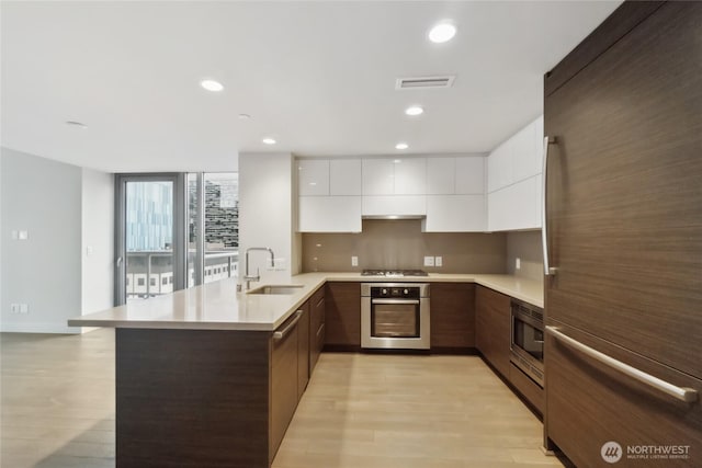 588 Bell St Unit 1603S, Seattle, WA 98121 - kitchen with appliances with stainless steel finishes, modern cabinets, a peninsula, a sink, and white cabinets