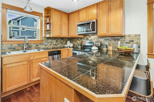 kitchen featuring a sink, appliances with stainless steel finishes, a peninsula, and tile countertops