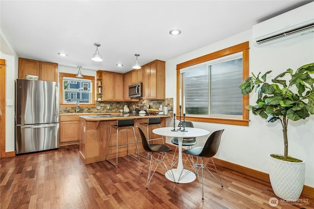 kitchen featuring decorative backsplash, wood finished floors, a wall mounted air conditioner, and stainless steel appliances