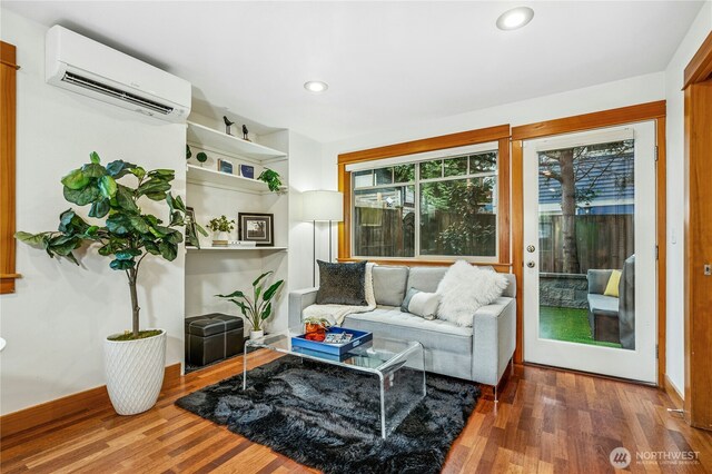 living area with recessed lighting, wood finished floors, baseboards, and a wall mounted AC