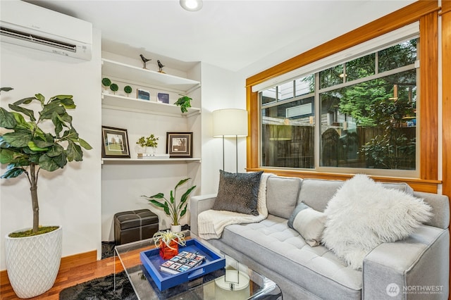 living area featuring baseboards, a wall unit AC, and wood finished floors