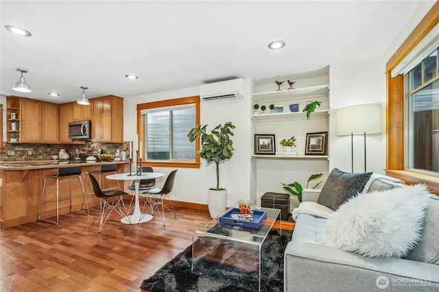 living room with an AC wall unit, recessed lighting, wood finished floors, and baseboards