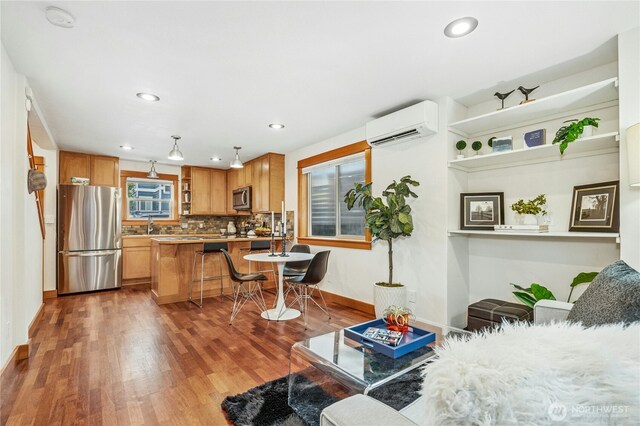 living area featuring an AC wall unit, recessed lighting, wood finished floors, and baseboards