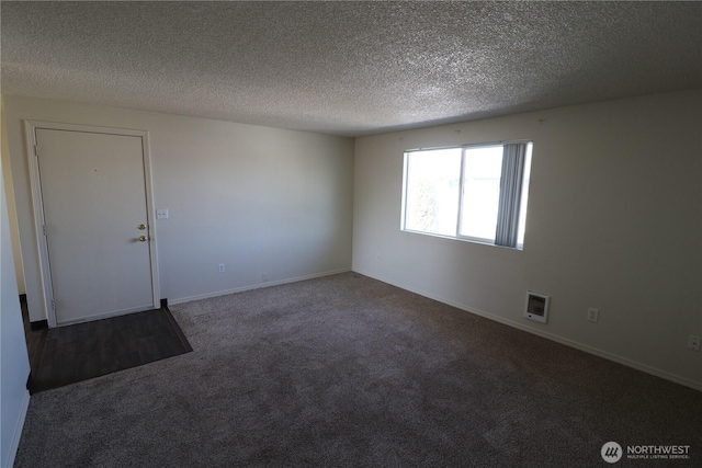 carpeted empty room featuring a textured ceiling and baseboards