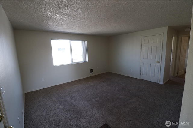 empty room featuring a textured ceiling, baseboards, and dark colored carpet