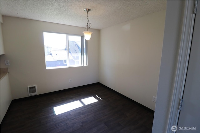 spare room featuring dark wood finished floors and a textured ceiling