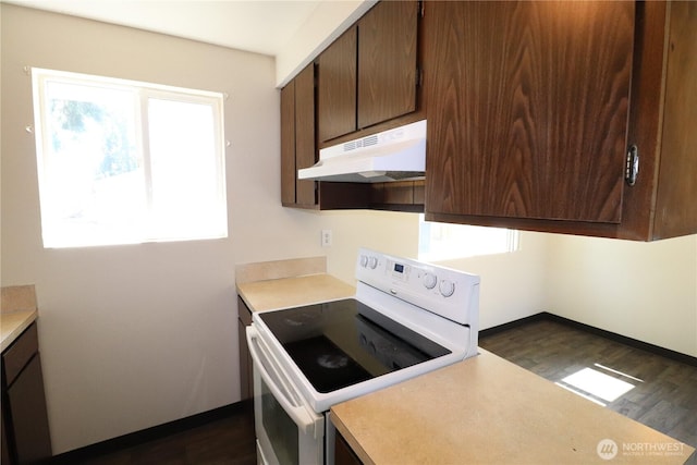 kitchen featuring under cabinet range hood, dark wood finished floors, light countertops, and white electric range