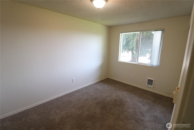 spare room with dark colored carpet, baseboards, and a textured ceiling