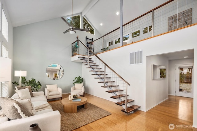 living room with visible vents, a high ceiling, a ceiling fan, and wood finished floors