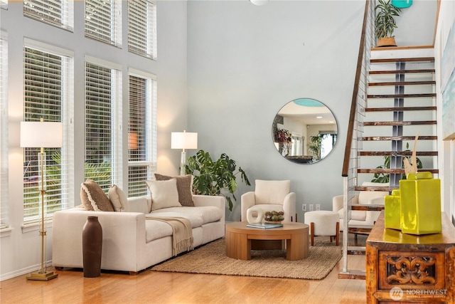 living area with baseboards, a high ceiling, wood finished floors, and stairs