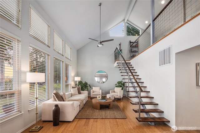 living area with plenty of natural light, wood finished floors, visible vents, and high vaulted ceiling