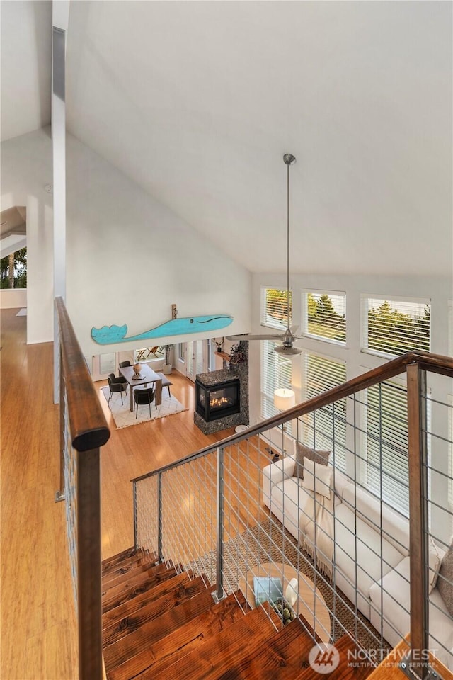 staircase featuring a glass covered fireplace, wood finished floors, and vaulted ceiling