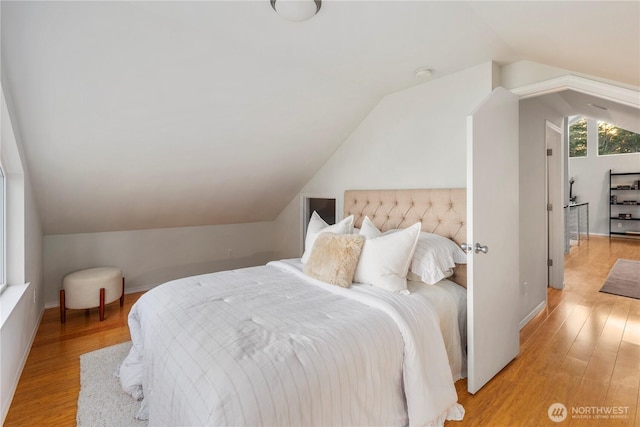 bedroom with baseboards, light wood-style floors, and vaulted ceiling