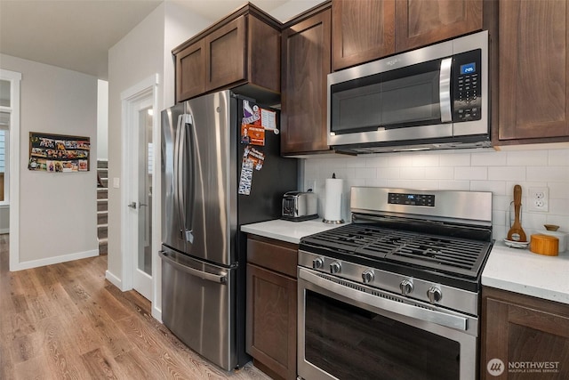 kitchen featuring tasteful backsplash, dark brown cabinets, light wood-style flooring, and appliances with stainless steel finishes