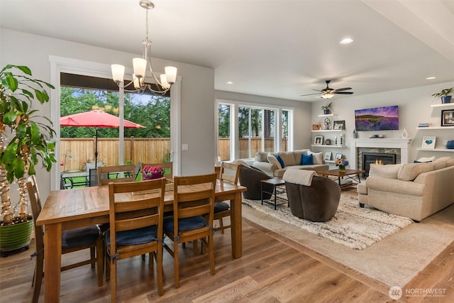 dining room featuring a glass covered fireplace, ceiling fan with notable chandelier, recessed lighting, and wood finished floors