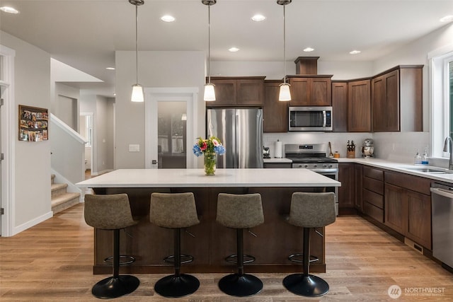 kitchen with a center island, light wood-style flooring, stainless steel appliances, and a sink