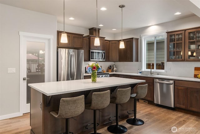 kitchen with a breakfast bar, backsplash, light wood-type flooring, and appliances with stainless steel finishes