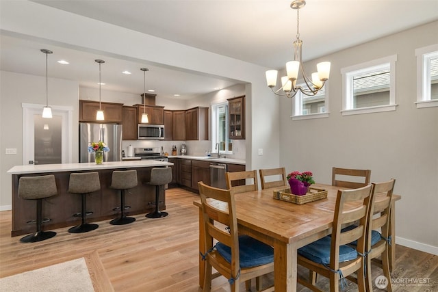 dining area with a chandelier, recessed lighting, light wood-type flooring, and baseboards