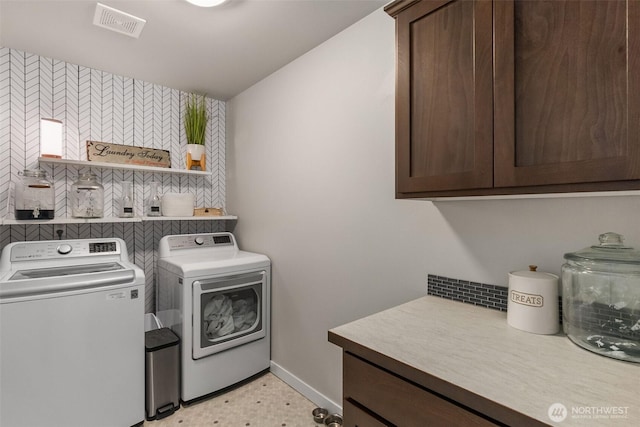 clothes washing area with baseboards, cabinet space, visible vents, and washing machine and clothes dryer